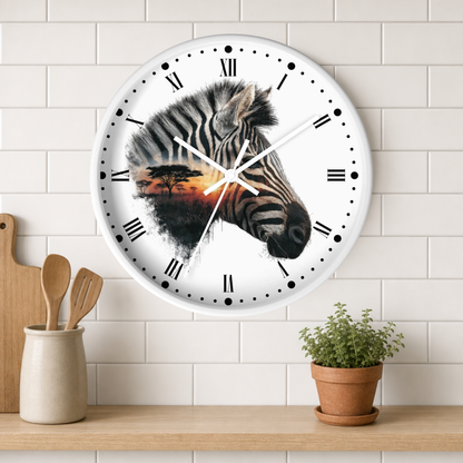 A round wall clock with a white face and black Roman numerals, featuring a zebra head graphic over an African savanna sunset scene. The clock is mounted on a white subway tile wall above a wooden shelf with a small potted plant and wooden utensils.