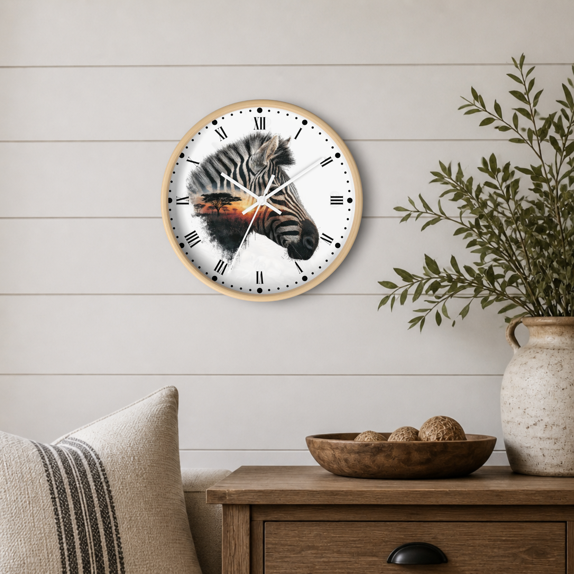 Round wall clock with a zebra face design on the face and a light wood frame, mounted on a white shiplap wall above a wooden side table with a vase and bowl.