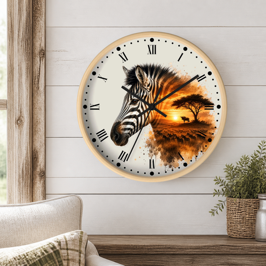 A round wall clock with a light wood frame hangs on a white shiplap wall above a wooden table. The clock face features a zebra head on the left and a warm sunset landscape with an acacia tree on the right, with black Roman numerals and hands.